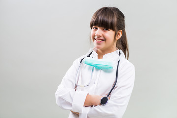 Portrait of beautiful little doctor on grey background.