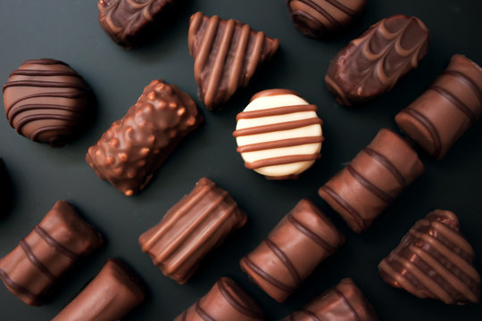 linea di cioccolatini di forme diverse su uno sfondo nero. tutte le caramelle bianco e cioccolato al latte, una rotonda caramelle bianco.