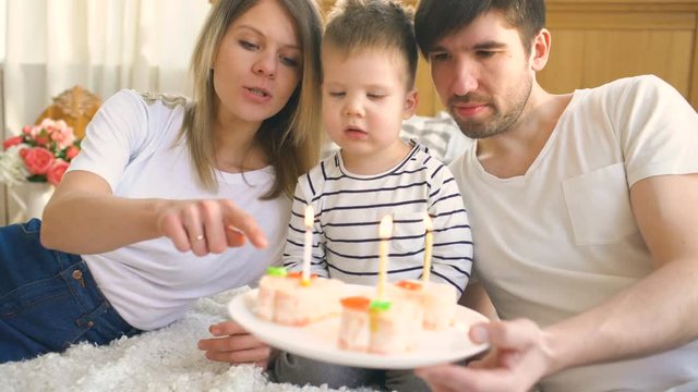Smiling family celebrating their son birthday together before blowing candles on cake