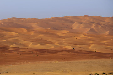 Fototapeta na wymiar empty quarter desert - lonely jeep driving to the dunes