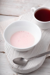 Fototapeta na wymiar Fruit yogurt and cup of tea on the white wooden table