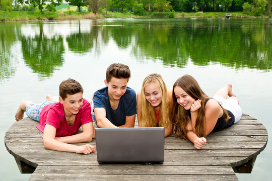 Gruppe Teenager / Jugendliche mit Notebook draußen in der Natur
