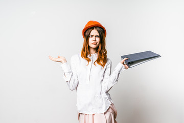 Young engineer with pensive face and security helmet isolated over white background question.Girl don`t understand in buildings.Woman questioned,raised arms