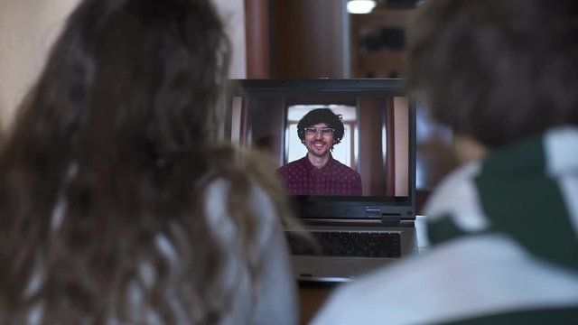 Man and woman talking with friend on laptop