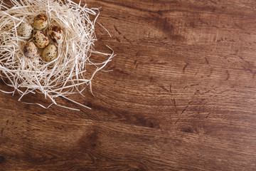 Quail eggs in straw nest. Natural organic eco food. Wooden rustic background.