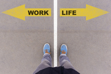 Work vs Life text arrows on asphalt ground, feet and shoes on fl