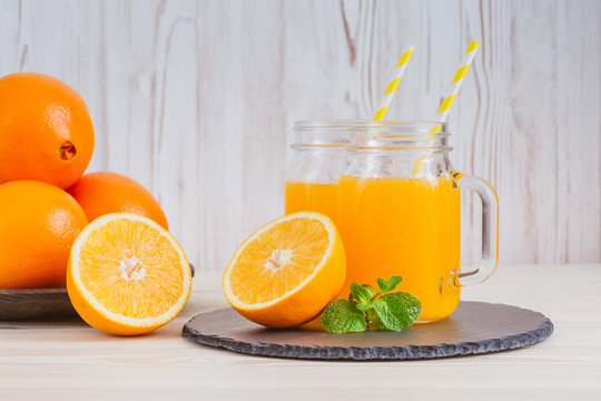 Fresh orange juice in a mason jar and orange sliced ripe on wooden table. Healthy eating concept.