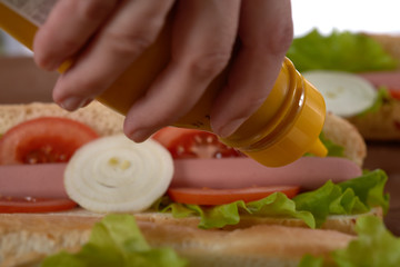 sandwich with sausage and vegetables on a wooden table