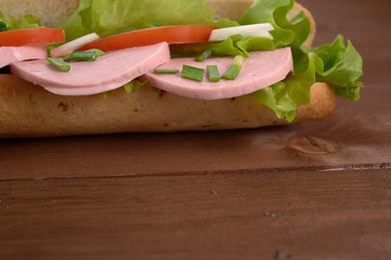 sandwich with sausage and vegetables on a wooden table