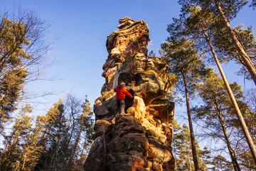 Kletterer steht am Fuß eines Sandsteinfelsen im Pfälzer Wald / Napoleonshut, Dahn, Rheinland-...