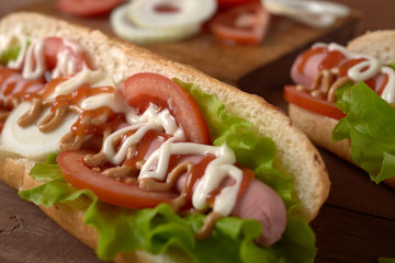 sandwich with sausage and vegetables on a wooden table