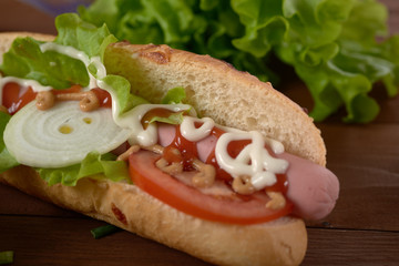 sandwich with sausage and vegetables on a wooden table