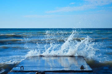 Sea waves crashing against the concrete pier