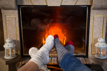 Legs in woolen socks heat up near fireplace