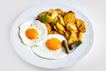 Two fried eggs with gherkin and roast potato