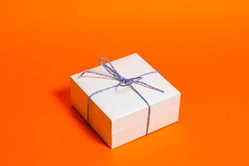 White gift box with bow on a orange background