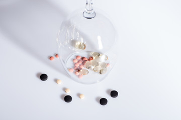 capsule and various pills inside wineglass