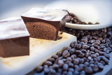 Hot coffee in a white cup and chocolate cake shot on a dark background.