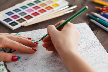 adult woman relieving stress by painting coloring book for relax