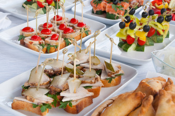 fast food, junk-food, catering and unhealthy eating concept - close up of canape hamburgers or sandwiches on serving tray