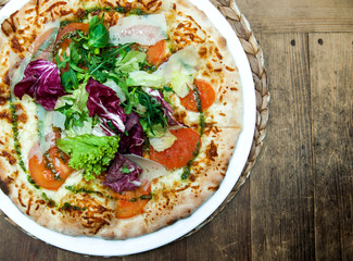 tasty pizza on wooden table with fresh green