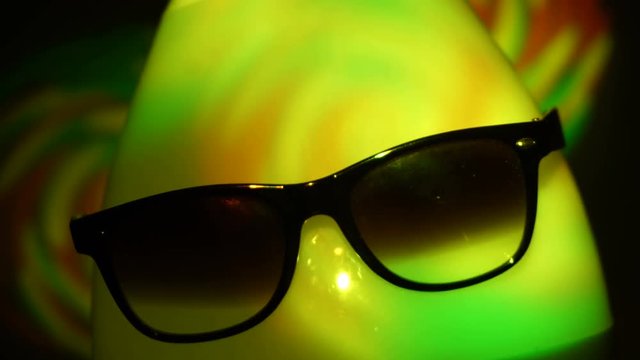 egghead man in sunglasses in the multicolored spotlight