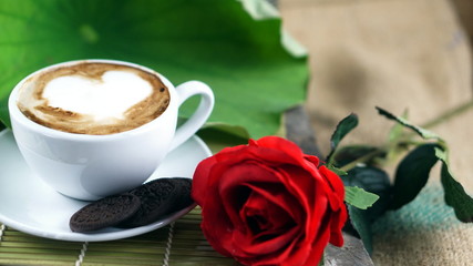 Cappuccino coffee and chocolate cookies. A cup of latte, cappuccino or espresso coffee with milk put on a wood table with dark roasting coffee beans and cookies. Drawing the foam milk on top.
