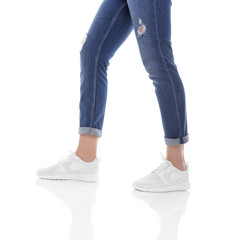 Women's legs in jeans and sneakers.