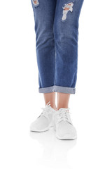 Women's legs in jeans and sneakers.