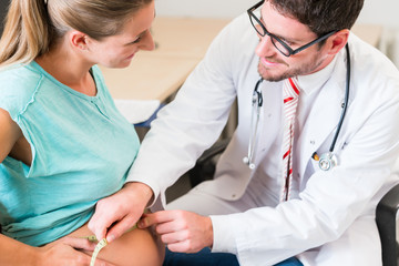 Gynecologist measuring belly of pregnant woman