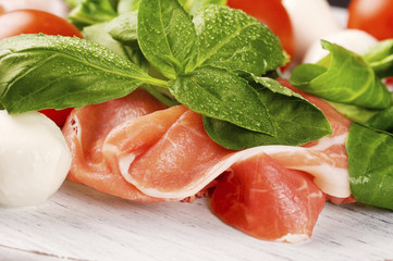 Prosciutto Smoked Pork Ham Rashers with tomato and mozzarella on the wooden table
