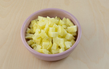 Raw chopped and diced apple cubes in small pink dish