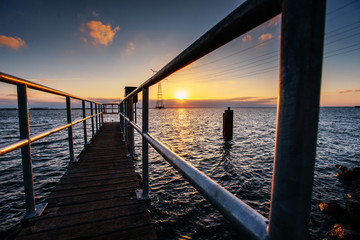 Fantastic sunset that illuminates the long pier on the lake