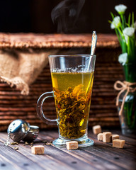 Hot tea in a transparent mug on wooden background