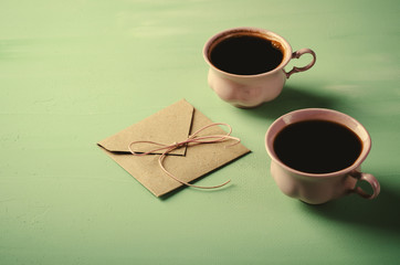 Love letter, envelope and two pink cups of coffee. Valentines card. Horizontal, flat lay