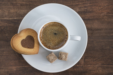 cup of coffee and cookie shaped heart on dark wooden background