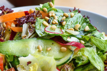 Close up photo of green healthy salad with ruccola, tomatoes, cucumbers, beet and seeds