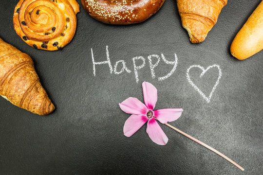 Fresh baked goods on a black background, the word "happy", pink