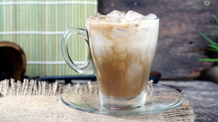 Ice Cappuccino coffee. A cup of latte, cappuccino or espresso coffee with milk put on a wood table with dark roasting coffee beans.