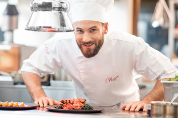 Portrait of chef cook in uniform with prepaired delicious dish at the restaurant kitchen