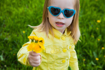Cute girl with funny sunglasses and bouquet of dandelions