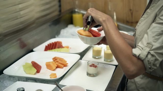 Young woman choosing fruit during breakfast at hotel, 4K
