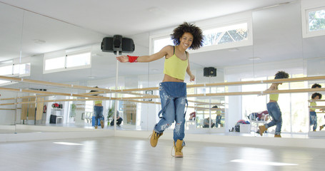 Adorable african american girl with huge afro haircut  dancing hip hop in studio. She wearing large...