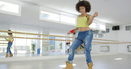 Beautiful and sexy female african american dancer shows her skills in studio. She wearing heavy work boots  and baggy jeans. Smiling to the camera