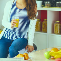Obraz premium Young woman sitting near desk in the kitchen
