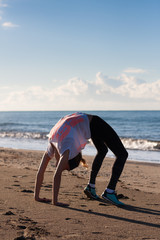 Young woman exercising on beach in crab position