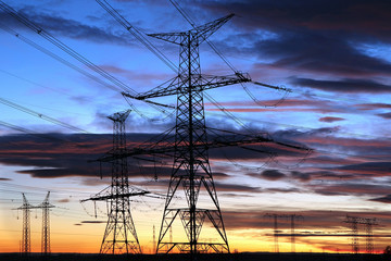 Silhouette of electricity pylons during sunset