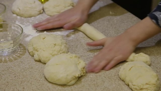 Cooking. Woman rolling pastry on light table near several dough pieces