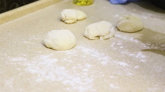 Making dough. Human hands roll out pieces with flour on light table