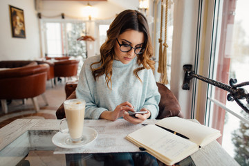  Business woman in glasses using smartphone in cafe